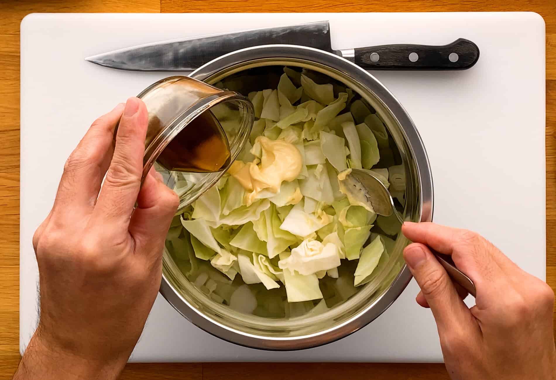 Japanese mayonnaise and sesame oil in bowl of chopped cabbage