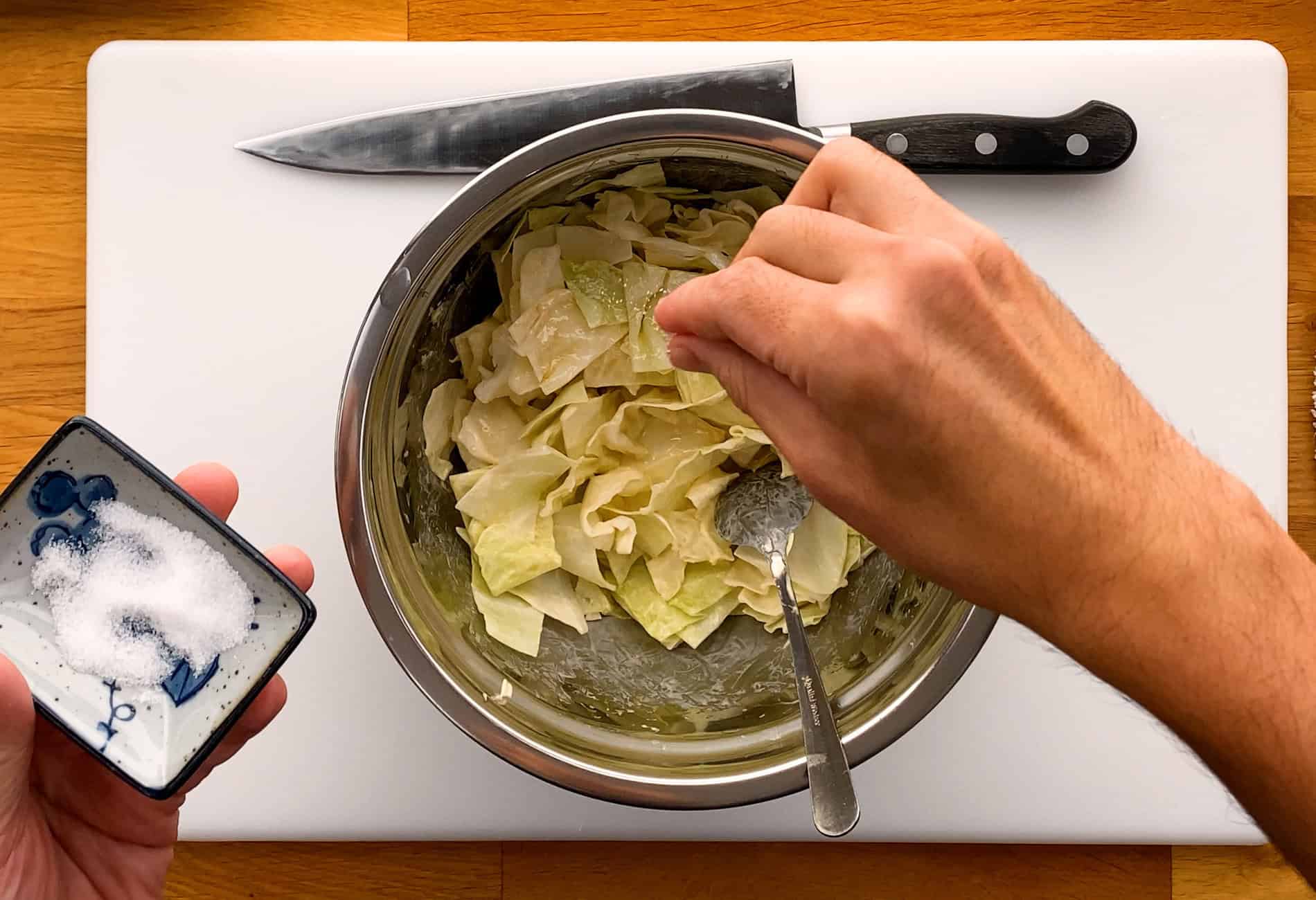 Adding salt into bowl of chopped cabbage