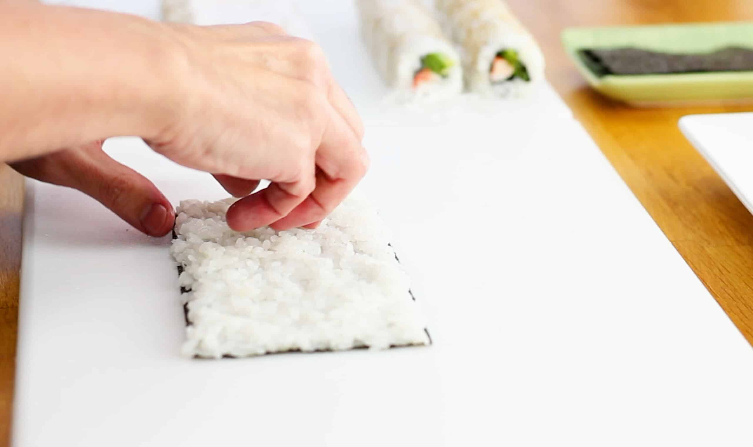 Spreading sushi rice on top of a nori sheet