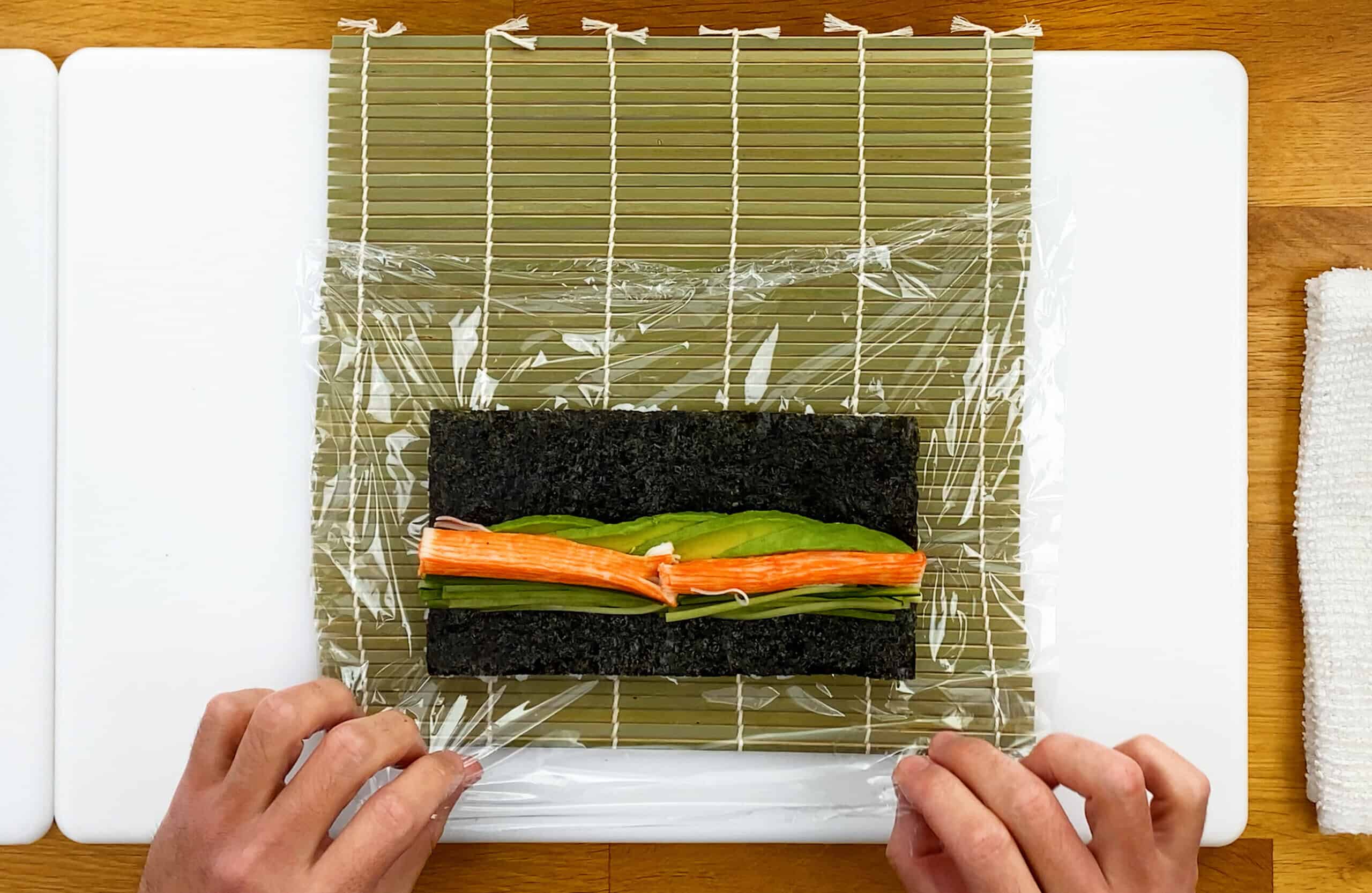 Rolling sushi with a sheet of plastic wrap and bamboo mat makisu