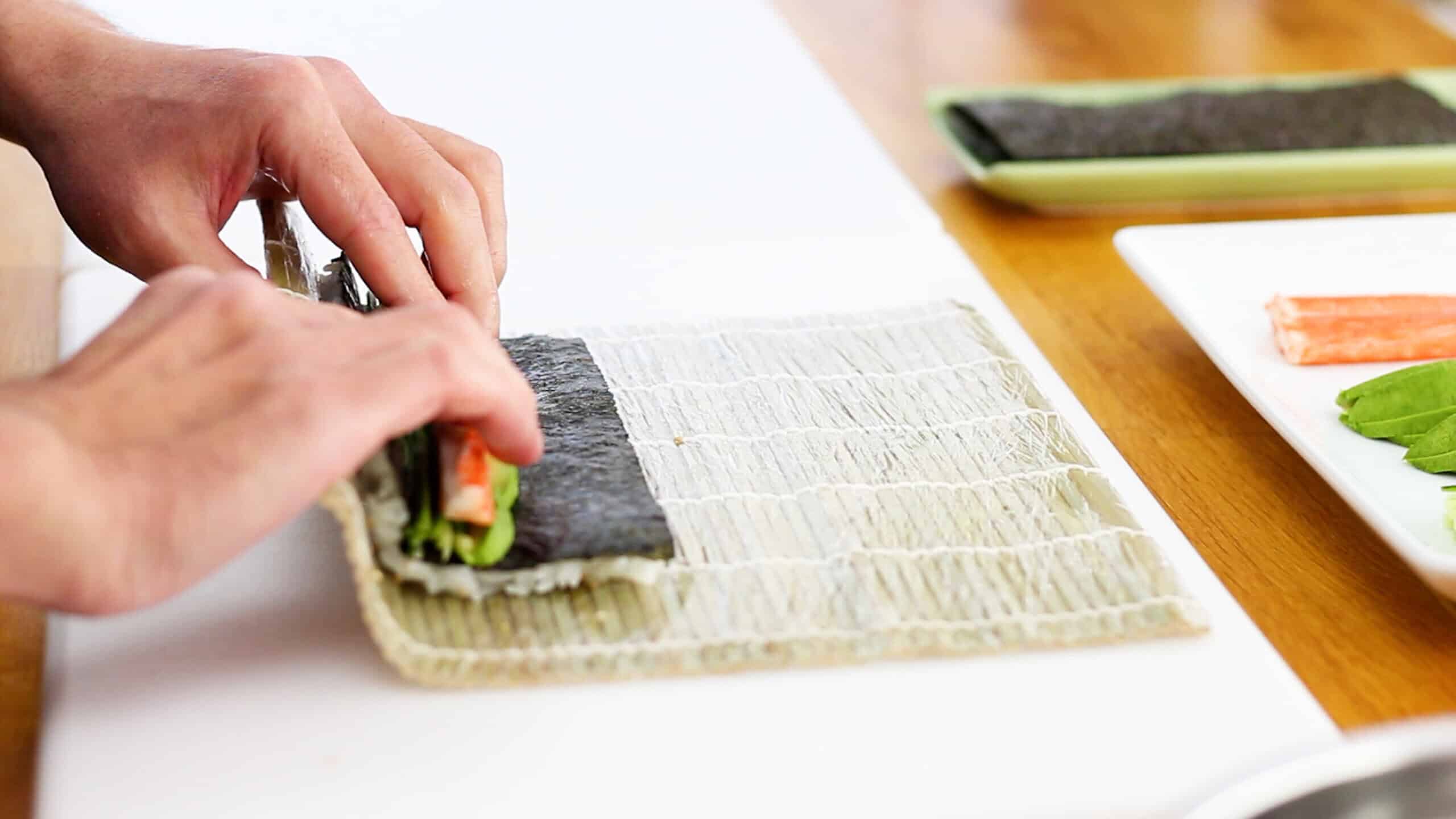 Rolling sushi with a plastic wrapped bamboo mat makisu