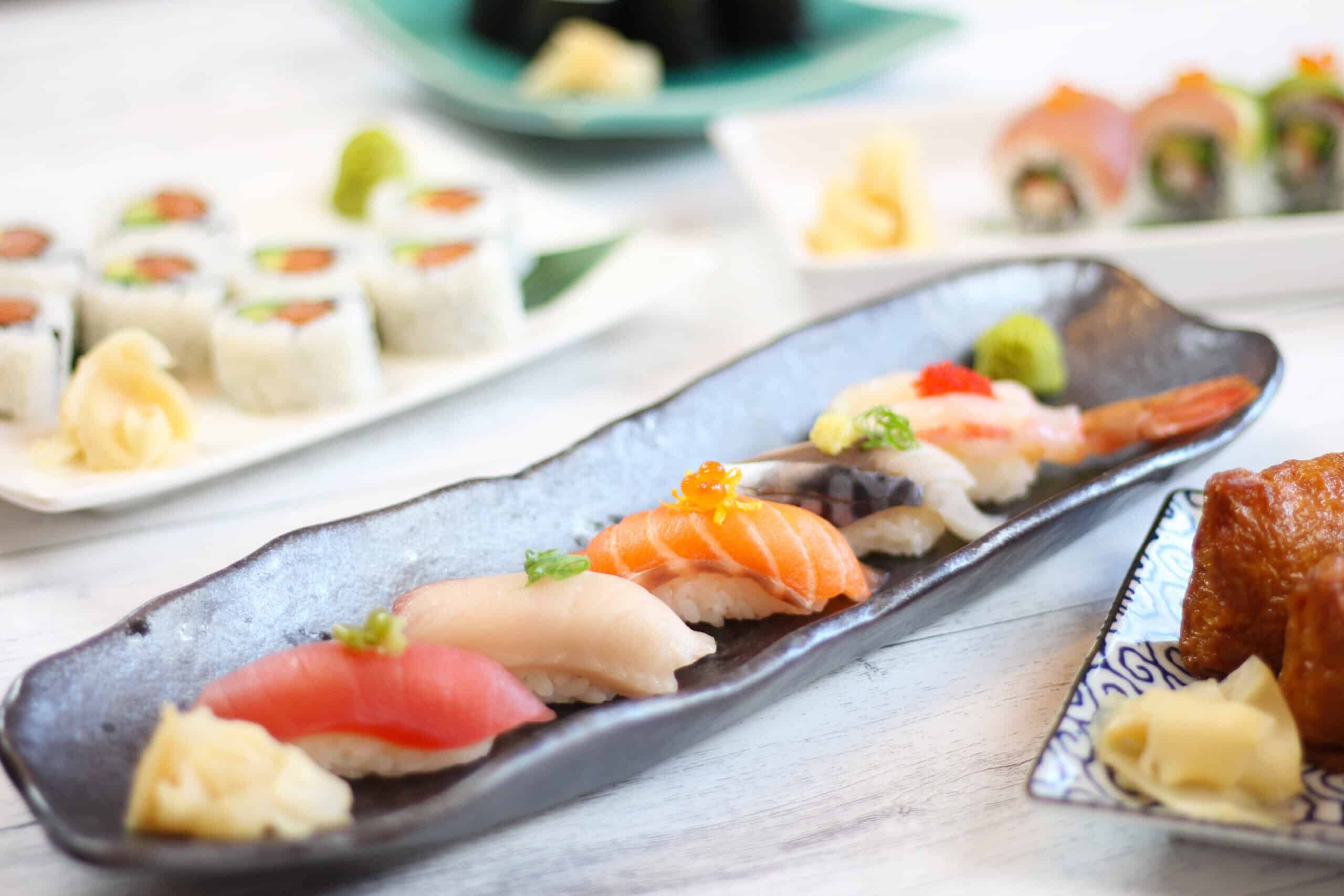 Variety of sushi on table - nigiri, rolls, inari