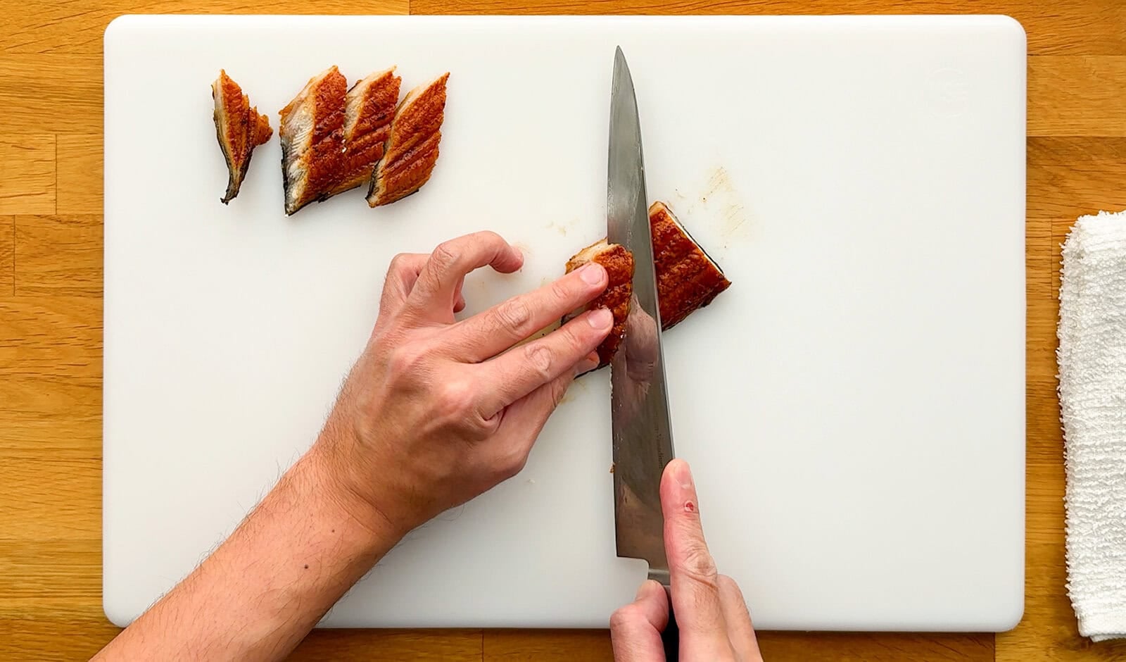 Cutting cooked unagi into thin diagonal slices for a Dragon Roll