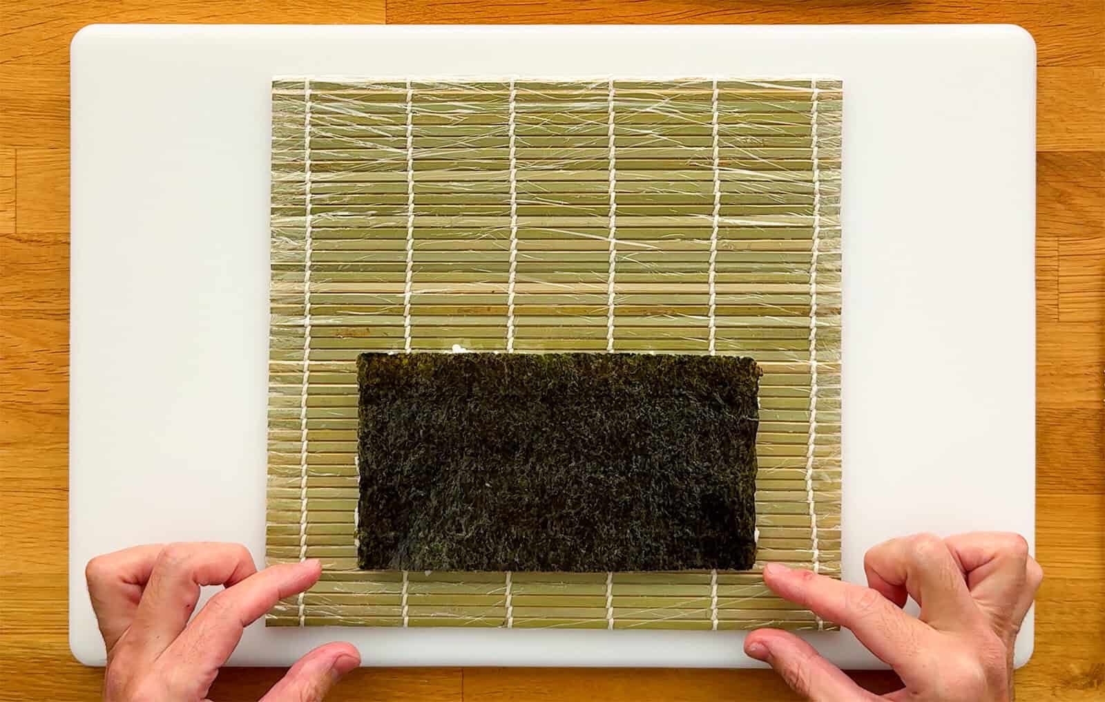 Flipped nori on a bamboo sushi rolling mat with a one-inch gap along the bottom edge