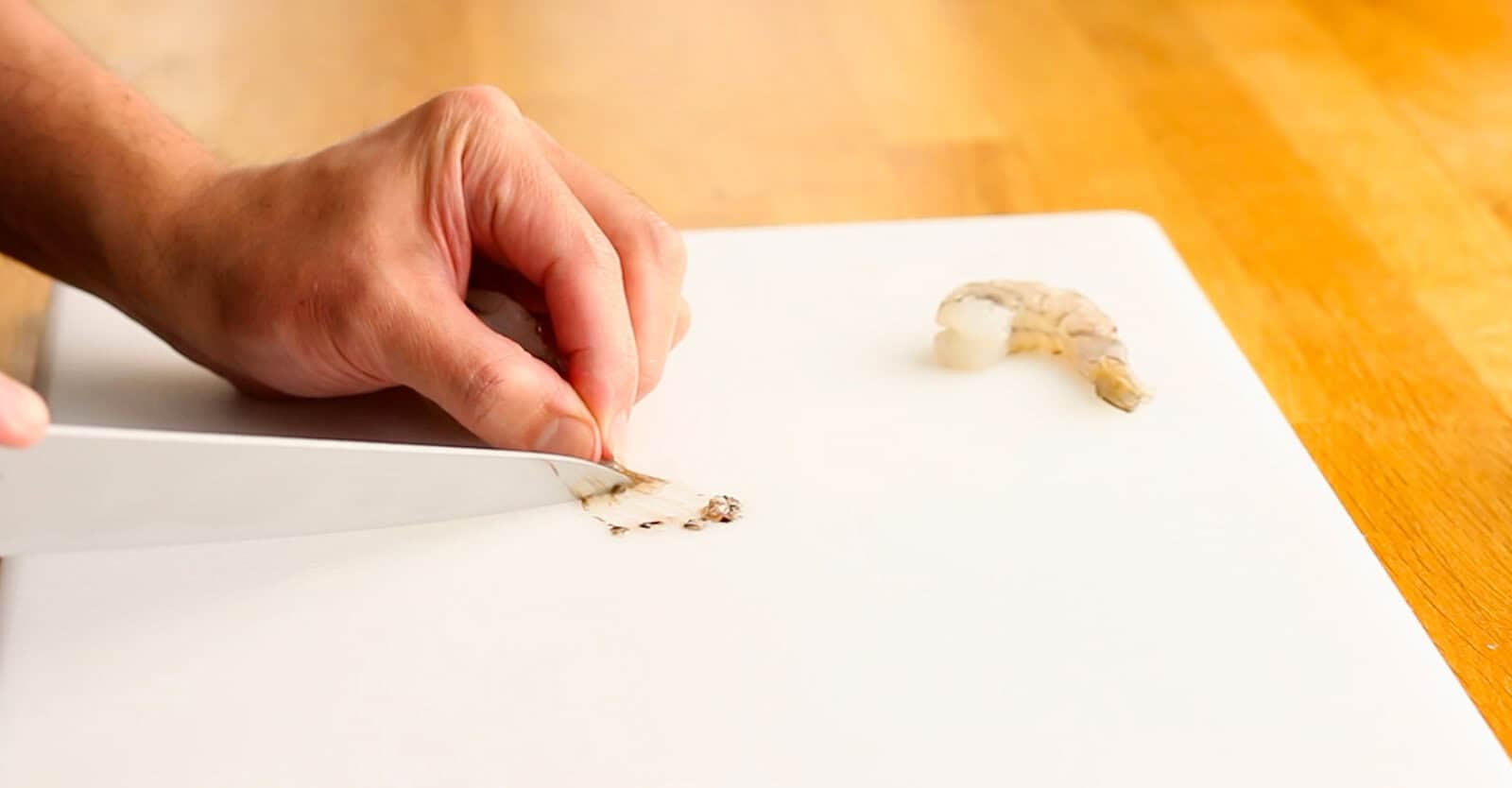 Scraping moisture and debris from a shrimp tail with a knife before making tempura
