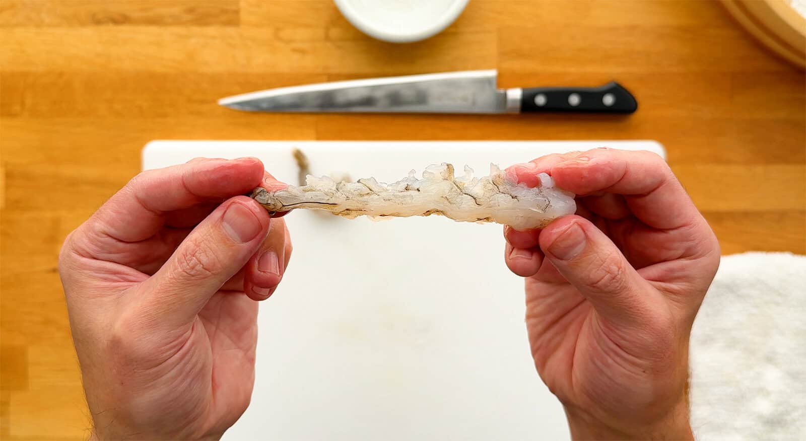 Holding a raw shrimp straight after preparing it for shrimp tempura