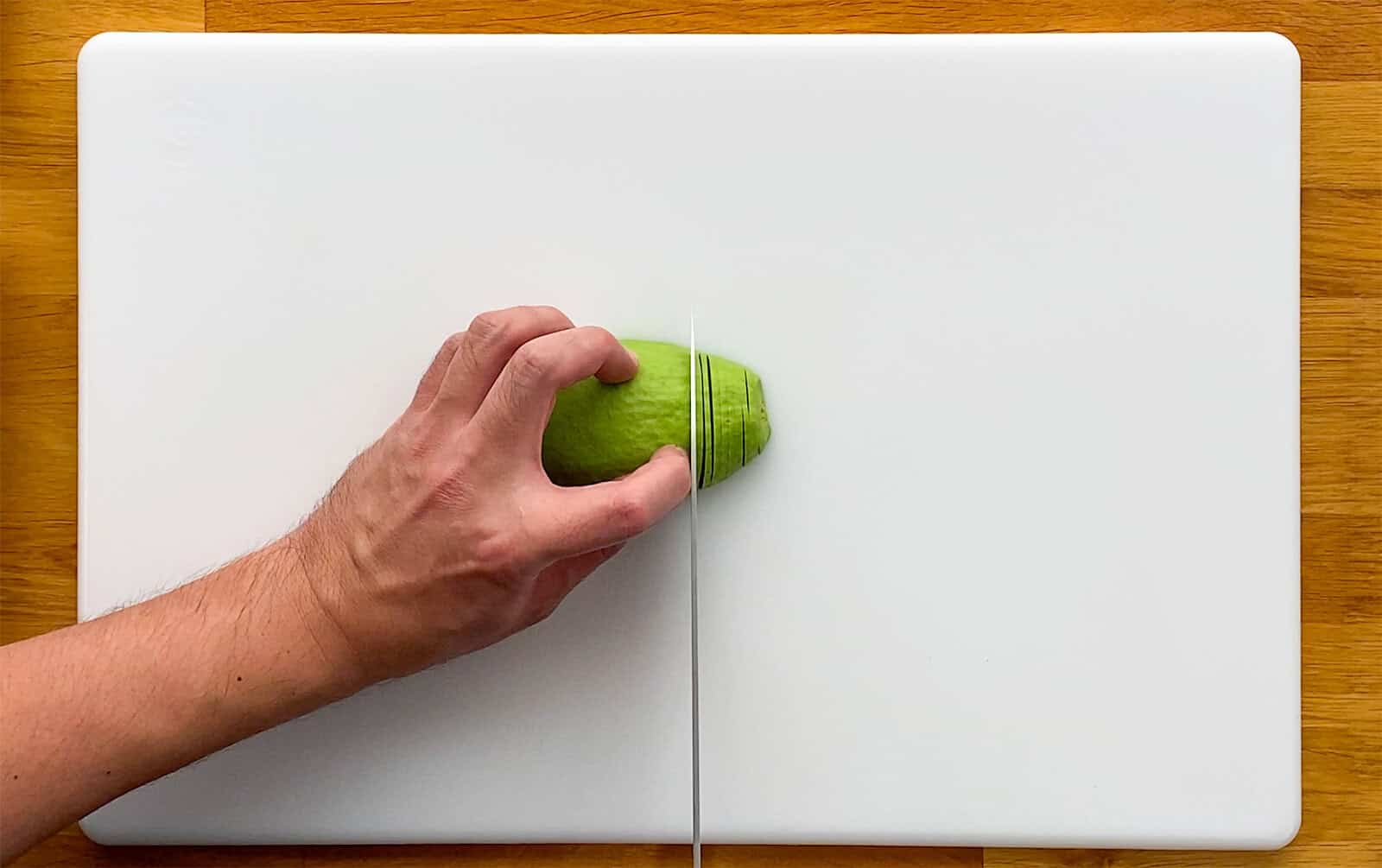 Cutting an avocado half crosswise into thin slices for Dragon Roll sushi